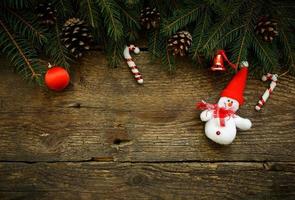 Christmas tree branches with christmas decorations and snowman on wooden texture photo