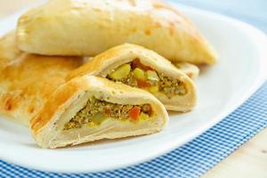 sabroso pastel relleno con carne en un blanco plato y azul a cuadros manteles foto