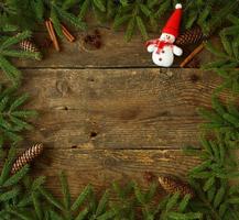 Christmas tree branch with cones, cinnamon, dittany and snowman on wooden background with copyspace photo