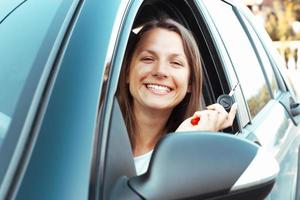 sonriente niña sentado en un coche y demostración llave foto