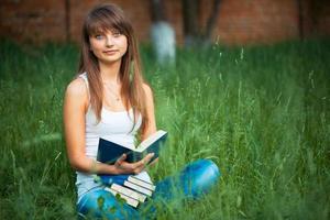 Beautiful girl with book in the park on green grass photo