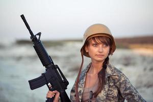 joven hermosa hembra soldado vestido en un camuflaje con un rifle foto