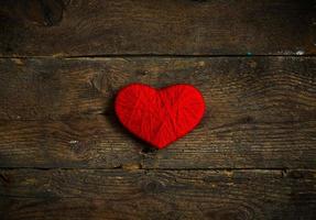 Red heart shape made from wool on old shabby wooden background photo