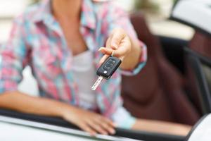 Woman standing near convertible with keys in hand - concept of buying a used car or a rental car photo