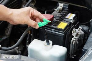 Mechanic's hand is opening bottle of water in car engine to Check auto car's coolant level. Concept , Checking and maintenance car service. photo
