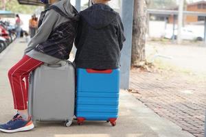 Closeup two boy travellers sit on their suitcases, baggage bags, wait for their parent to pick them up home after sumer camp activity. Concept, journey, find real life experiences for kids. photo