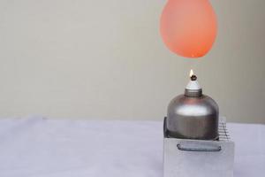 Balloon with water filled is burned on fire flame of metal lantern. Concept, science experiment. Fireproof balloon demonstration. Balloon with water inside doesn't pop under flame. photo