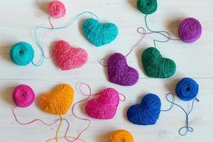 Multicolored Hearts with a balls of thread on white wooden background photo