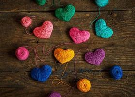 Multicolored Hearts with a balls of thread on old shabby wooden background photo