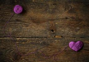 Purple Heart with a ball of thread on on old shabby wooden background photo