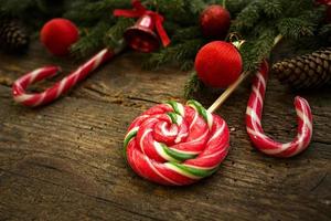 Borde de Navidad con ramas de abeto, conos, adornos navideños y bastón de caramelo sobre tablas de madera rústica foto