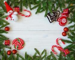 Navidad frontera con abeto árbol sucursales, Navidad decoraciones y caramelo caña en blanco de madera tableros foto