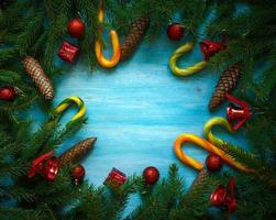Christmas border with fir tree branches, cones, christmas decorations and candy cane on blue wooden boards photo