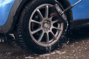 Hand wash with soap, pink foam on the body. Car washing with high pressure water. photo