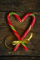 Candy canes in the heart shape on a wooden background photo