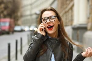 sorprendido mujer de negocios caminando abajo el calle mientras hablando en teléfono inteligente foto