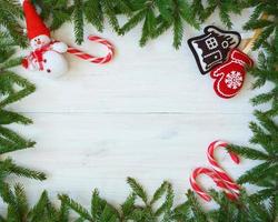 Christmas border with fir tree branches, christmas decorations and candy cane on white wooden boards photo