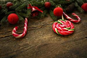 Christmas border with fir tree branches, cones, christmas decorations and candy cane on rustic wooden boards photo