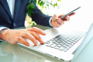 Men office worker typing on the keyboard and using smartphone photo