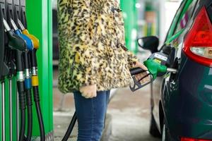 mujer llena gasolina dentro su coche a un gas estación en invierno foto