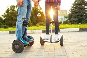 Young couple riding hoverboard - electrical scooter, personal eco transport, gyro scooter, smart balance wheel photo