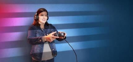hermosa joven Hispano mujer en pie jugando con un vídeo juego consola en su manos en contra Violeta azul pared antecedentes foto