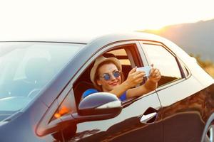 Woman in hat and sunglasses making self portrait sitting in the car photo