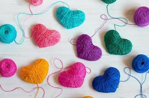 Multicolored Hearts with a balls of thread on white wooden background photo