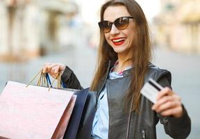 hermosa mujer con compras pantalones y crédito tarjeta en el manos en un calle foto