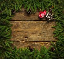 Christmas border with fir tree branches, cones and christmas decorations on rustic wooden boards photo