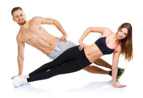 Attractive sport couple - man and woman doing fitness exercises on the white photo