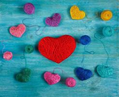 Multicolored Hearts with a balls of thread on blue wooden background photo