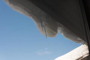 Snow and ice melting. Roof of a wooden house photo