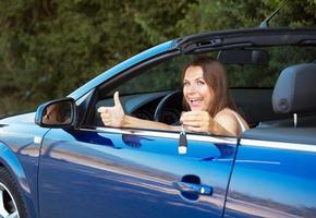 Smiling caucasian woman showing key in a cabriolet photo