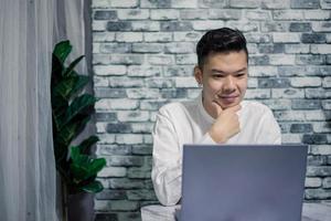 retrato de contento empresario trabajando a hogar con ordenador portátil en escritorio foto