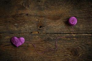 Purple Heart with a ball of thread on on old shabby wooden background photo