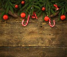 Christmas border with fir tree branches, cones, christmas decorations and candy cane on rustic wooden boards photo