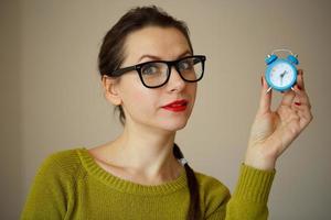 Little blue alarm clock in the hands of young woman photo