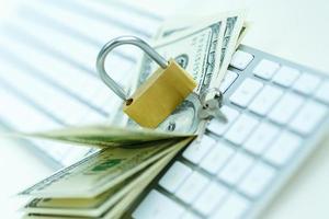 Security lock on dollar bills with white computer keyboard photo