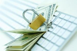 Security lock on dollar bills with white computer keyboard photo