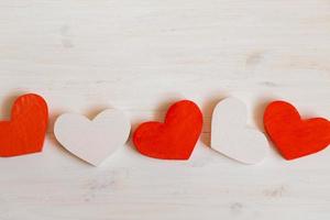 Red and white hearts on white wooden background photo