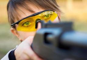 un joven niña con un pistola para trampa disparo y disparo lentes foto