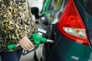 mujer llena gasolina dentro su coche a un gas estación en invierno foto