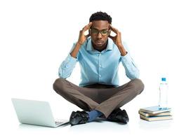 Happy african american college student with laptop, books sitting on white background photo