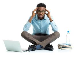 African american college student in stress sitting with laptop, books and bottle of water on white photo