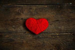 rojo corazón forma hecho desde lana en antiguo desgastado de madera antecedentes foto