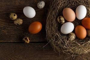 Chicken and quail eggs in a nest on a wooden rustic background photo