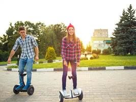 A young couple riding hoverboard - electrical scooter, personal eco transport, gyro scooter, smart balance wheel photo