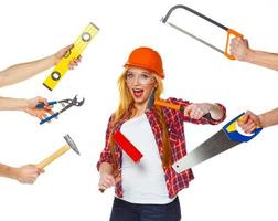 Funny girl in a helmet with different tools is isolated on the white photo