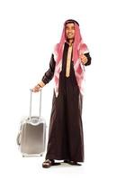 Young smiling arab with a suitcase and thumb up isolated on white photo